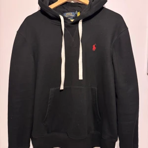 Polo Ralph Lauren - Fleece hoodie - RL Fleece Hoodie är en klassisk och bekväm huvtröja perfekt för vardagsbruk. Den har en avslappnad passform och en mjuk fleecefodring för värme och komfort. Huvtröjan har en känguruficka för extra bekvämlighet och en dragsko i huvan för en anpassningsbar passform