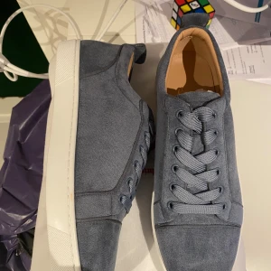 Ljusblå loubs - Snygga blå loubs med klassisk röd sula och vit yttersula. Skorna har ovandel i mocka, rund tå och breda snören. Perfekta för dig som vill ha en stilren men ändå lyxig look.