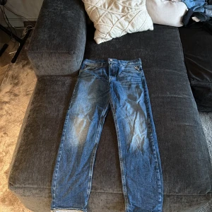Blå jeans från Replay, modell Thad - Snygga blå jeans från Replay i modellen Thad. Klassisk femficksdesign med Replay-logga på myntfickan och läderpatch bak. Jeansen har en rak passform och är tillverkade i slitstarkt denim med coola slitningar och kontrastsömmar.