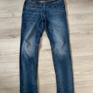 Blå jeans från Jack & Jones, storlek 32/34 - Snygga blå jeans från Jack & Jones i klassisk straight fit med fem fickor och orangea kontrastsömmar. Jeansen har normal passform och är tillverkade i slitstarkt denim med lätt tvättad look. Perfekt för dig som gillar stilrena och bekväma jeans. Passar dom som är lite över 180. Skriv för mer bilder med mera