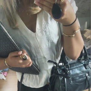 Vit v-ringad blus med knappar - Säljer en fräsch vit blus med v-ringning och knappar framtill. Modellen har trekvartsärm och smockad midja som ger en snygg siluett. Perfekt för dig som gillar en clean och stilren look.