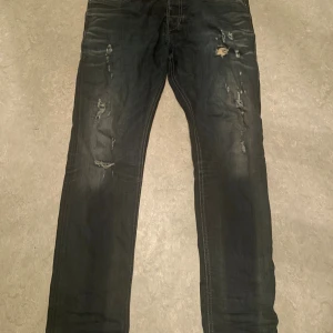 Diesel Tepphar mörkblåa slim jeans W33 L32 - Mörkblåa Diesel Tepphar jeans med slim fit och stretch. Snygga slitningar och trasiga detaljer. Hör av er för fler frågor.