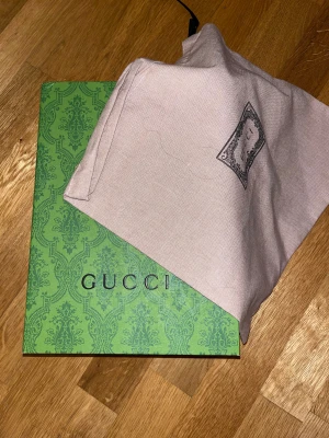 Gucci keps med blått GG-mönster - Säljer en snygg Gucci keps i storlek M med klassiskt blått GG-mönster och en ikonisk röd-blå rand på sidan. Kepsen är tillverkad i manchester och har justerbar rem baktill. Kommer med original dustbag och grön Gucci-box.