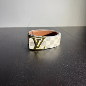 Bälte  - Helt nytt bälte i vitt rutig färg med guldig logga 