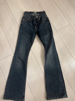 Blå bootcut jeans från Gina Tricot - Snygga blå jeans från Gina Tricot i klassisk bootcut-modell. Jeansen har fem fickor, normal passform. Perfekta för dig som gillar en tidlös look med lite utsvängda ben. Storlek 34.