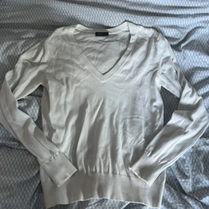 Vit v-ringad tröja Peak Performance - Vit v-ringad tröja från Peak Performance i storlek M. Tröjan har långa ärmar och ribbade muddar vid ärmslut och nederkant. Perfekt för dig som gillar clean och enkel stil. Klassisk design som funkar året runt. Änvänd men i fint skick 