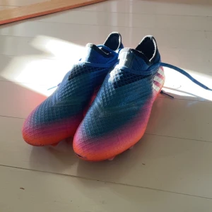 Adidas Messi blå-orange fotbollsskor - Säljer ett par Adidas Messi fotbollsskor. Mycket bra skick använda en gång! Lite trasishs där framme men annars ingenting! Storlek 41 1/3! Pris går att diskutera 