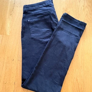 Esmara Slim Jeans - Svarta cargopants från Esmara med raka ben och stora fickor framtill. Byxorna har klassisk midja, bälteshällor och knappstängning. Tillverkade i ett mjukt bomullsmaterial som är skönt att bära hela dagen.