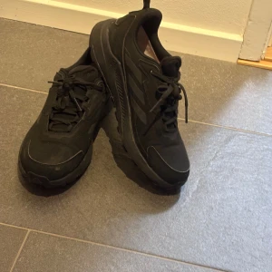 Svarta Adidas Terrex sneakers - Svartas Adidas Terrex sneakers med robust sula och snygga detaljer. Perfekt för vintern! Skorna har snörning, mesh och syntetmaterial för extra komfort och andningsförmåga. Perfekta för dig som gillar en sportig och clean look. Ikoniska tre ränder på sidan och Terrex-logga på innersulan.