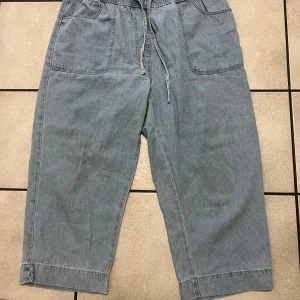 Blå croppade jeansbyxor från Cellbes - Snygga ljusblå croppade jeansbyxor från Cellbes med elastisk midja och snörning. Byxorna har två stora framfickor och är tillverkade i mjukt jeansmaterial. Perfekt för en chill och avslappnad stil.