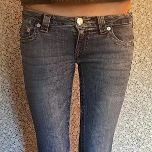 True Religion bootcut jeans blå - Säljer ett par snygga blå jeans från True Religion med klassisk bootcut och ikoniska bakfickor med kontrastsömmar. Jeansen har låg midja och är tillverkade i mjukt denim med lätt tvättad look. Info från Nelly: Jeans från True Religion  Stretchigt material  Ultra low waist  Flared fit  Dekorativa sömmar på fickorna baktill 