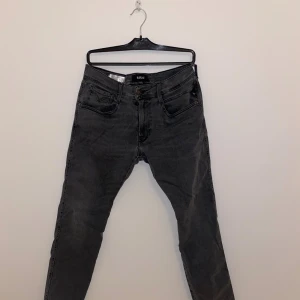 Replay svarta jeans slim fit - Svarta jeans från Replay med fem fickor och klassisk design. Jeansen har en slim passform och är tillverkade i stretchigt tygg för extra komfort. Snygga detaljer på bakfickorna och läderpatch med Replay-logga i midjan.