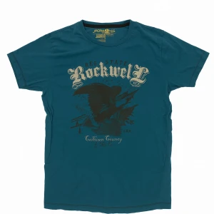 Blå t-shirt Jack & Jones Rockwell - Snygg blå t-shirt från Jack & Jones med tryck framtill där det står 'Rockwell' och en stor örn. Klassisk rund hals och korta ärmar. Skön bomullskvalitet som passar perfekt till jeans eller shorts.