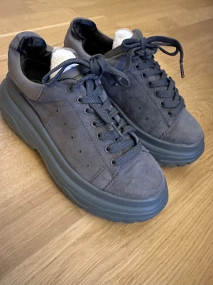 Missguided Chunky Skor, Sneakers, Grå S37 - Säljer ett par grå chunky sneakers med plattformssula och snörning. Ovandelen är i mocka och har en rund tå. Snyggt grov mönstrad sula som ger extra höjd och cool vibe. Perfekt för dig som gillar streetstyle och vill sticka ut med dina skor.