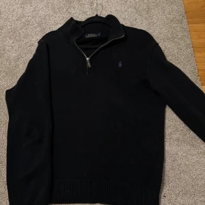 Svart stickad half zip från Polo Ralph Lauren - Svart stickad tröja från Polo Ralph Lauren med half zip och ribbad krage. 