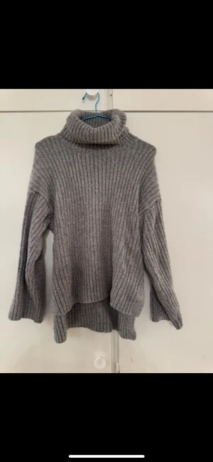 Stickad tröja  - ribbad stickad tröja från gina storlek s. Slit med längre bakdel och polokrage. 