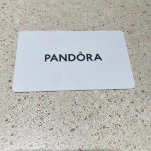 Presentkort Pandora 1198 kr - Presentkort från Pandora med värde 1198 kr, perfekt för att köpa snygga smycken som armband, ringar, halsband eller örhängen i deras butiker i Sverige, Danmark och Norge. Kortet är vitt med svart logga och gäller i 5 år från utfärdande.