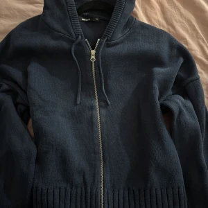 Mörkblå stickad hoodie med dragkedja - Mörkblå stickad hoodie från bikbok i storlek XS. Tröjan har huva med snörning, hel dragkedja framtill och bred ribbad kant nedtill