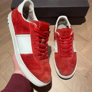 Valentino flycrews röda sneakers mocka - Snygga Valentino flycrews sneakers i rött och vitt med mocka och skinn. De har röda snören, vit panel på sidan och coola nitar på hälen. Yttersulan har ett unikt mönster och insidan är vit. Perfekt för dig som vill sticka ut med exklusiva sneakers.