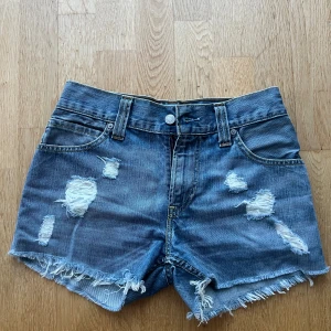 Levi's 511 Slim blå jeansshorts - Säljer ett par Levi's 511 Slim jeansshorts i klassisk blå denim med slitna detaljer och fransig kant.