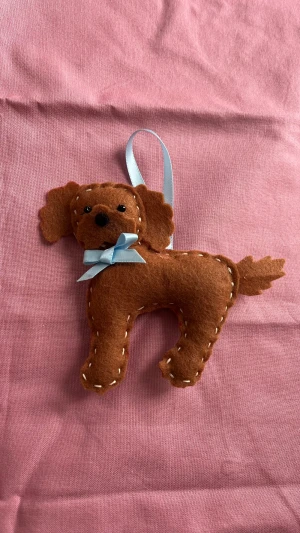 Handgjort julgranshänge hund med rosett 🎄 unikt & sött julpynt - Supergullig handgjord hund i brun filt med ljusblå rosett runt halsen och band för upphängning. Dekorationen har broderade detaljer och mjuk form, perfekt som personlig prydnad eller present till någon som älskar hundar. 💌Packeteras och skickas med omsorg.