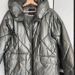 Silver Mohito pufferjacka - Säljer en riktigt snygg quiltad pufferjacka i metallic silver med stor huva och dragkedja framtill. Jackan har två stora fickor och coola snörningsdetaljer vid huvan. Perfekt för en kall vinter! Använd endast nån gång då den är lite för stor för mig. Skitsnygg! Pris går att diskutera❤️