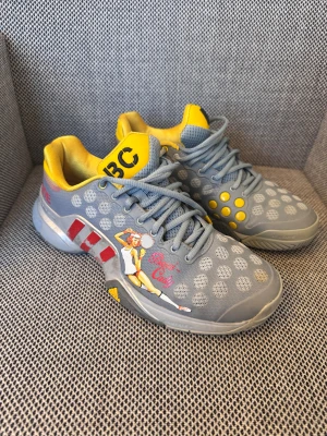 Adidas Barricade lucky lady - Unika Adidas Barricade sneakers i grått med coolt retro-tryck av en tennisspelare på sidan. Skorna har gula och röda detaljer, prickigt mönster och snörning. Insidan är gul och yttermaterialet är syntet med meshpaneler för extra ventilation. Perfekt för dig som gillar sportig och färgstark stil.