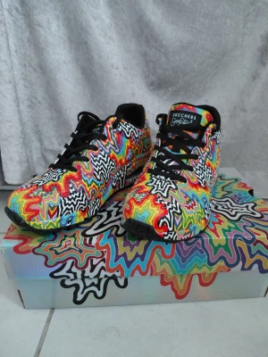 Skechers sneakers med psykedeliskt mönster - Färgglada Skechers sneakers med psykedeliskt, vågigt mönster i svart, vit, röd, gul, blå, grön, orange och lila. Skorna har svarta snören, rund tå och platt sula. Ovandelen är i syntetmaterial och insidan är svart. Perfekt för dig som gillar att sticka ut med din stil. MINSTA JAG KAN GÅ ÄR 500!!!