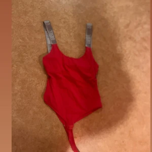 Röd body från Diesel - Snygg röd body från Diesel med grå axelband där Diesel-loggan är tryckt i vitt.  