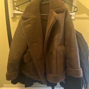 Brun teddyjacka från Topshop XS - Säljer en brun teddyjacka från Topshop i storlek XS. Jackan har bred krage, stora fickor och mjukt teddyfoder både inuti och utanpå. Perfekt för dig som gillar en chill och cozy vibe under höst och vinter. Snyggt oversize med uppvikta ärmslut och detaljerad sömnad.