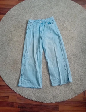 Ljusblå wide jeans - Säljer ett par ljusblå jeans med breda ben.. Byxorna har normal midja och är tillverkade i denimtyg. Perfekta för dig som gillar avslappnad och trendig stil.