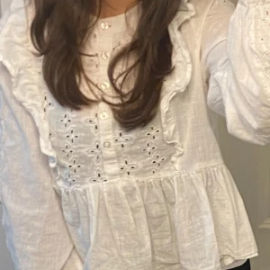Vit broderad blus från Bik Bok - Supersöt vit blus från Bik Bok med broderade detaljer och volanger längs bröstet och axlarna. 
