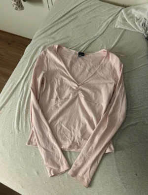 Ljusrosa långärmad topp Gina Tricot - Säljer en ljusrosa långärmad topp från Gina Tricot i mjuk bomull. Toppen har v-ringning med snygg rynkdetalj framtill och en feminin, slim passform. Perfekt att styla med jeans eller kjol för en chill look. Använd 1 gång ❤️ skriv för frågor 