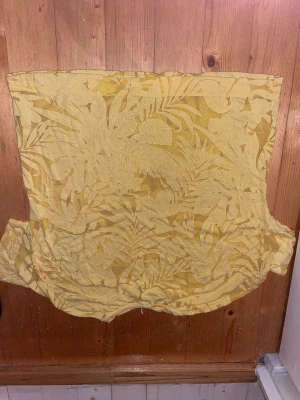 Gul t skjorta  från Stradivarius - Säljer en gul genomskilnig t skjorta   från Stradivarius i storlek M. Toppen har ett tropiskt blommigt mönster i ton-i-ton och är ganska loose. Materialet känns mjukt och lätt, perfekt för varma dagar. Snygg att styla med jeans eller kjol för en fräsch look , för stor för mig ❤️❤️❤️