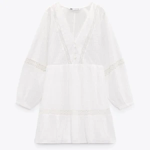 Vit kort klänning från Zara - Jättefin kort sommarklänning från Zara med v-ringning, knappar framtill och spetsdetaljer. Har rätt så tunt tyg men är samtidigt inte super genomskinlig, perfekt till sommaren! 