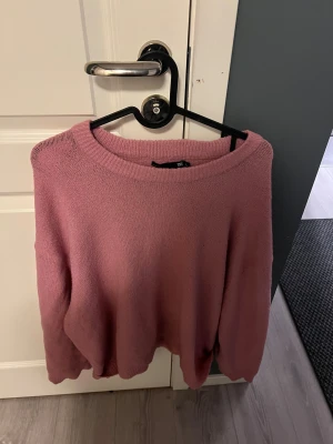 Rosa stickad tröja med rund hals - Mysig rosa stickad tröja i storlek L med rund halsringning och långa ärmar. Perfekt för att hålla sig varm under kyliga dagar. Enkel och stilren design som är lätt att matcha med jeans eller kjol.
