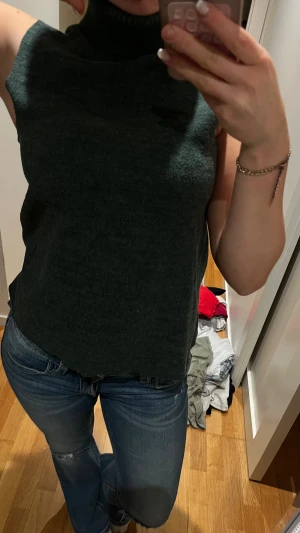 Mörkgrön polotopp från ZARA - Snygg mörkgrön polotopp från ZARA i stickat material. Toppen är ärmlös med hög polokrage och har en loose passform som ger en chill vibe. Perfekt att styla med jeans eller kjol för en cool look. Materialet är mjukt och ribbat vid kragen.