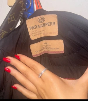 Svart Parajumpers lång dunjacka med päls - Säljer min svarta Parajumpers lång dunjacka med fluffig päls på huvan och gul detalj vid halsen. Jackan har dragkedja, knappar och snörning nedtill. Perfekt för kalla dagar och har en riktigt snygg, stilren look som är enkel att matcha. 