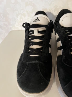Adidas skor  - Ett par fina svarta adidas skor med mocka. Sulan på skorna är skadade.  För mer bilder hör av dig 