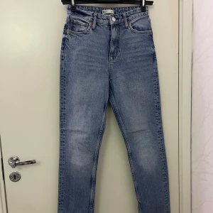 Blå jeans med slits från Gina Tricot - Snygga blåa jeans från Gina Tricot med raka ben och hög midja. Jeansen har klassisk femficksdesign och coola slitsar nertill på benen. Tillverkade i denim med en skön passform, perfekta till sneakers eller att klä upp med klackar.