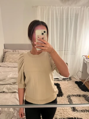 Beige puffärm tröja med ribbad kant - Säljer en beige tröja med puffiga ärmar och ribbad kant vid hals från Lindex. Är it exakt säker på storlek men mellan XS-S