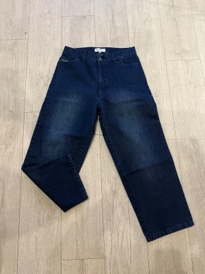 Mörkblå jeans från Yardsale, storlek S - Snygga mörkblå jeans från Yardsale med raka ben och broderad logga på fickan. Klassisk femficksmodell med knapp och dragkedja i gylfen. Jeansen har en relaxed passform och är tillverkade i robust denim med cool Yardsale-detalj på bakfickan.
