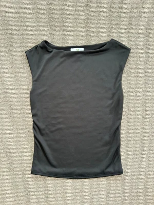 Svart ärmlös topp från Live in the moment sleeveless tröja  - Snygg svart topp från Live in the moment i storlek S. Modellen är ärmlös med breda axlar och har en stilren, slät design utan mönster. Materialet känns mjukt och stretchigt, perfekt för en clean och enkel look. Passformen är normal och toppen är lätt att matcha med allt.