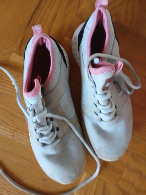 Turkosa och rosa sneakers med snörning - Snygga sneakers i turkos med rosa detaljer och svart parti vid hälen. Skorna har snörning, mesh-tyg upptill för extra andningsförmåga och en platt sula. Perfekta för dig som gillar sportig och fräsch stil.