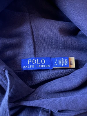 Ralph Lauren Hoddie - Snygg Polo Ralph Lauren hoodie i en stilren brun färg. Mjuk, varm och perfekt för dig som gillar clean vardagsstil.  Skick: ✔ Bra skick ✔ Inga hål eller fläckar ✔ Mjuk innerfleece ✔ Klassisk Polo-passform  Detaljer: • Storlek: S • Färg: Brun • Broderad logga • Bekväm och kvalitativ hoodie