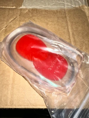 Röda och transparenta hälkuddar Comfort Heel Cups - Ett par Comfort Heel Cups. Säljer ett par mjuka hälkuddar i transparent och rött silikonmaterial. Perfekta att lägga i sneakers eller andra skor för extra komfort och stötdämpning. Kommer i försluten plastpåse och är lätta att använda i olika skotyper.Perfekta för dig som har hälsporre, ömma hälar eller bara vill ha extra dämpning i vardagsskorna. Inläggen ger stabilitet, minskar belastningen och gör promenader betydligt skönare.