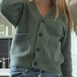 Grön kofta från Arket  - Mysig grön kofta från Arket i storlek XS. Koftan har v-ringad hals, fyra mörka knappar framtill och två stora fickor. Materialet är stickat och känns mjukt och fluffigt, perfekt för lager-på-lager. Använd ett fåtal gånger i somras men har bara legat och skräpar i garderoben sen dess! Nypriset är runt 1000 kr. Tveka inte att fråga vid funderingar! 