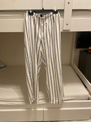 Randiga byxor  - Snygga vita byxor med svarta vertikala ränder från SHEIN i storlek 36. Materialet känns lätt och luftigt, perfekt för dig som gillar en chill och trendig look. 