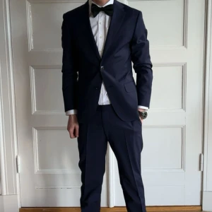 Mörkblå kostym med kavaj och byxor - Snygg mörkblå kostym med klassisk kavaj och matchande byxor från Oscar Jacobsson! Nypris på allt är 6000kr storlek på kavajen är 44 och byxor 46 jag är 182,5 och byxorna sitter Pefekt men lite liten i kavajen men den funkar absolut skulle rekommenderas för 178-180cm lång 