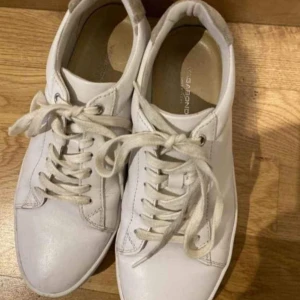 Vita sneakers från Vagabond, strl 37 - Säljer ett par klassiska vita sneakers från Vagabond i storlek 37. Skorna har rund tå, snörning och är gjorda i skinn med textilfoder och syntetsula. Perfekta till jeans eller kjol för en clean look.